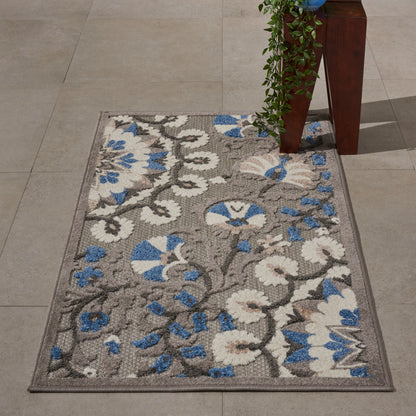 Rectangular area rug with gray base and white/blue floral pattern; tufted, low-pile synthetic fibers, for living room or entryway.