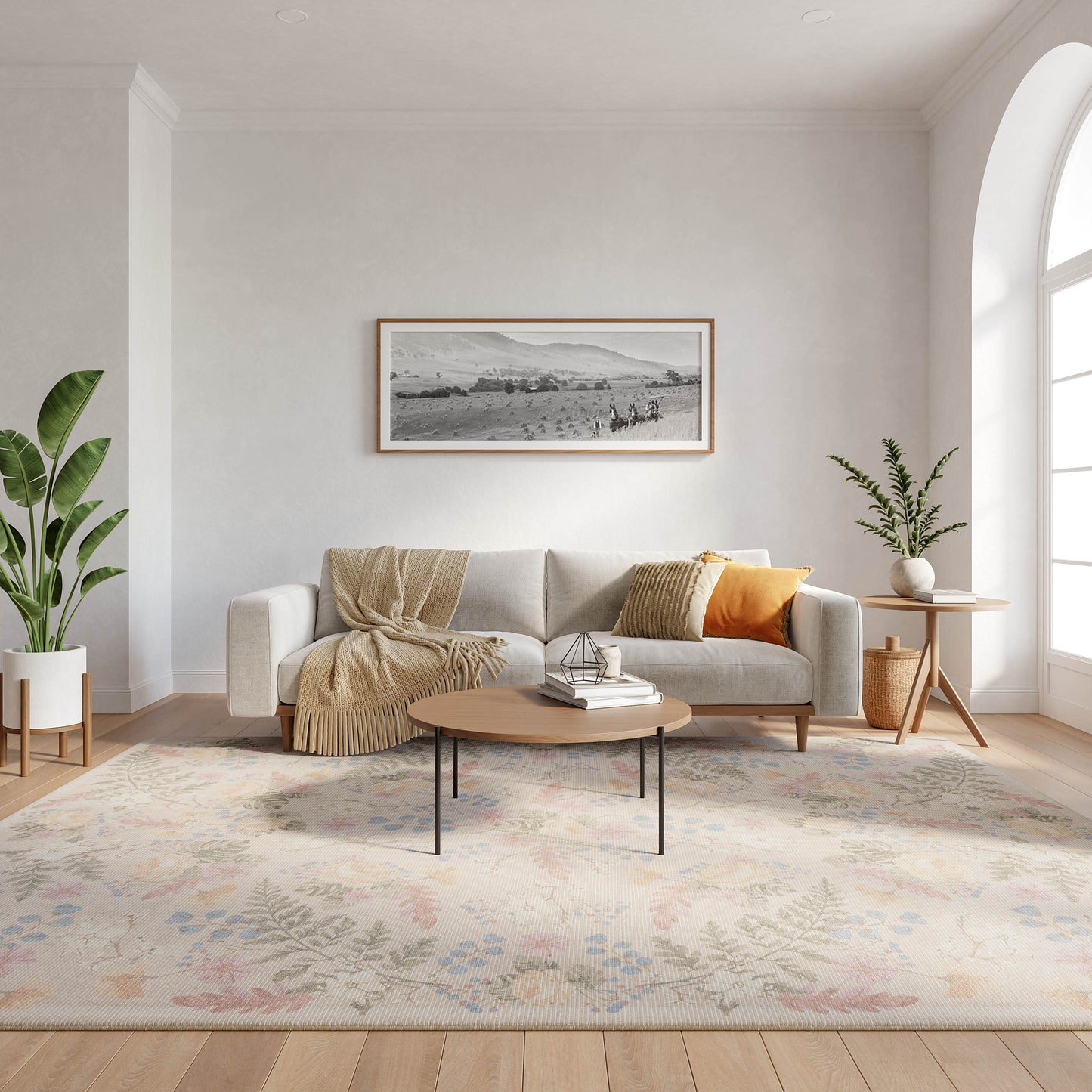 Light gray minimalist living room with a beige sofa, mustard pillow, round wood coffee table, pastel rug and potted plants.