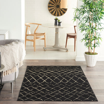 Black rug with white lattice pattern on light wood floor in a bright living room with a round glass table.