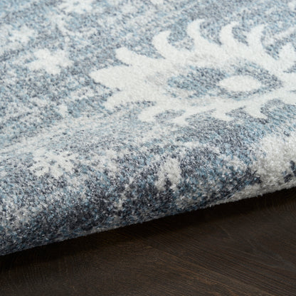 Blue and white snowflake-pattern rug with plush pile, folded edge on dark wood floor.