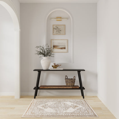 Black console table with white vase and greenery, a woven basket, framed art in an arched niche, and beige rug.