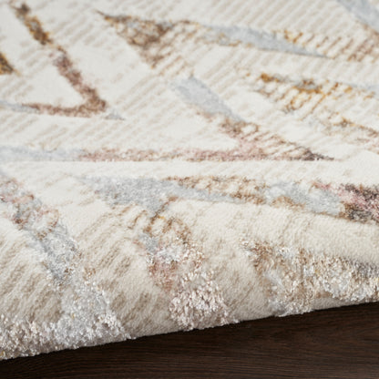 Close-up of cream rug with abstract beige-brown-gray geometric pattern and soft pile on dark wood floor.