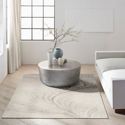 Light minimalist living room with a modern rug, grid window, and decorative vases with blossoming branches.