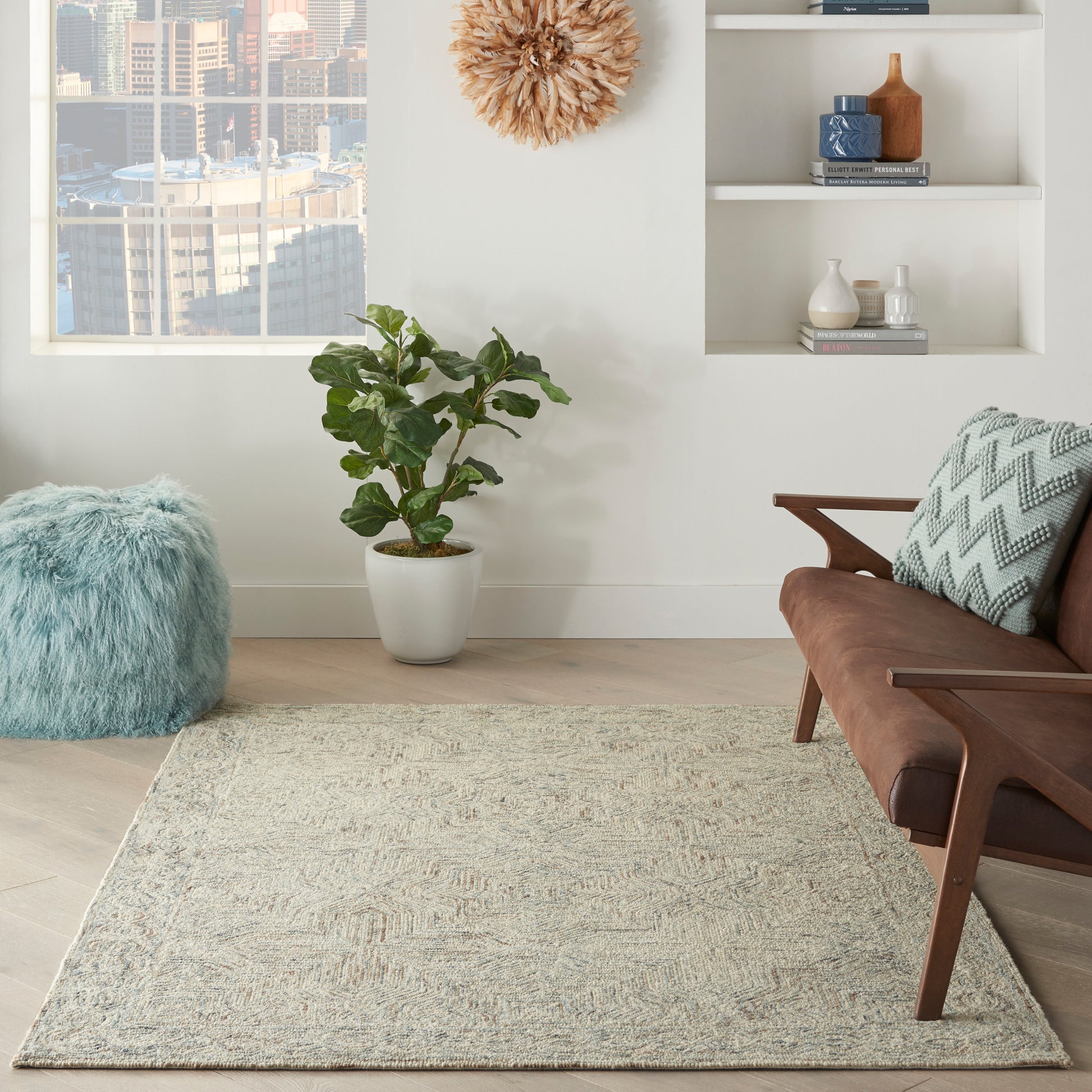 Neutral beige textured rectangular area rug in a modern living room with a mid-century brown sofa, blue pouf & plant.
