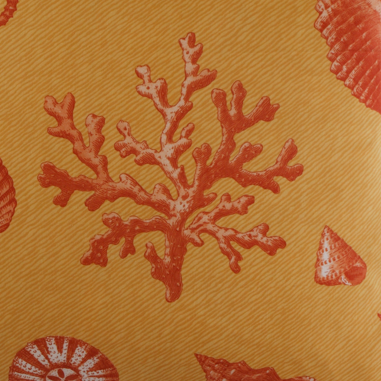 Orange pillow with red coral branches and seashells in a tropical reef motif.