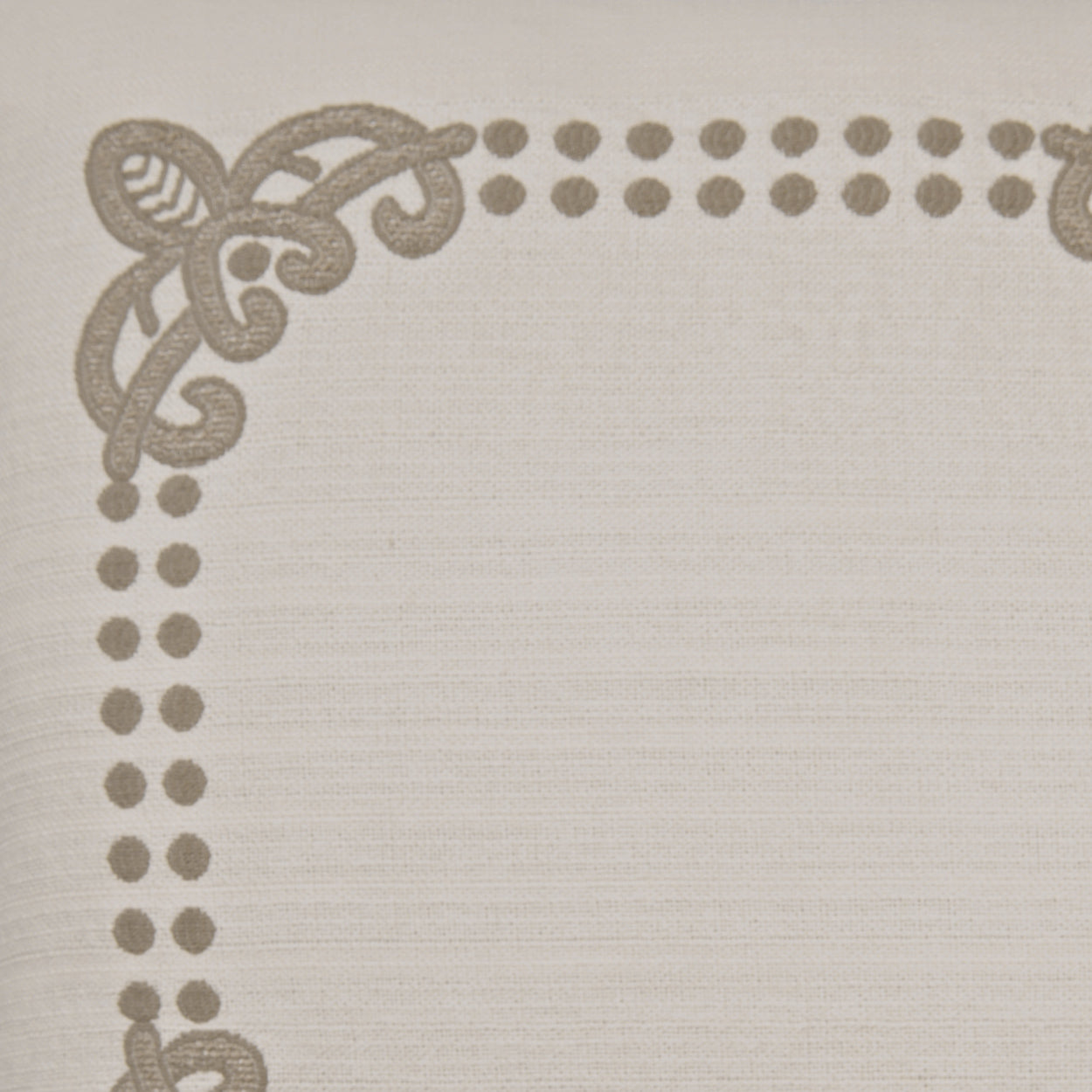 Beige fabric with taupe ornate corner scrollwork and dotted border along edges.