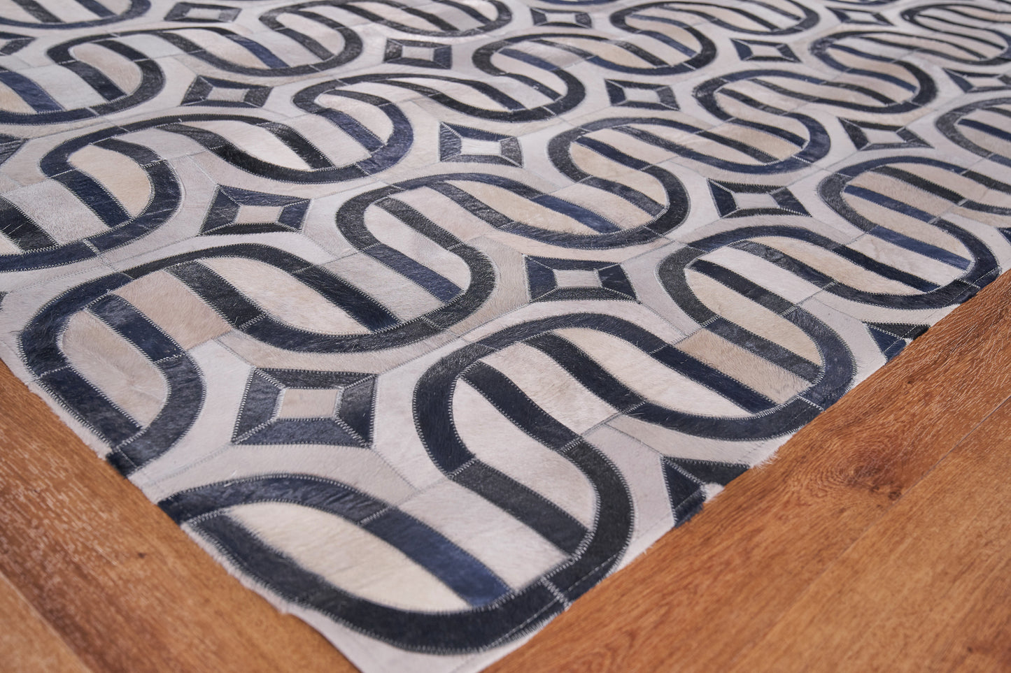 Geometric beige and navy rug with interlocking loop pattern on a wooden floor.