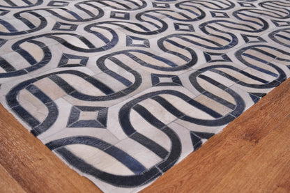 Geometric beige and navy rug with interlocking loop pattern on a wooden floor.