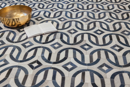 Natural hide indoor hand-stitched rug on a floor, showing textured weave and natural color variation.