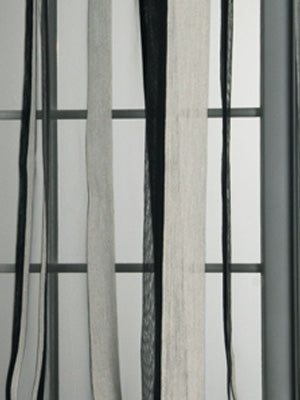 Close-up of black, white, and gray striped drapery fabric swatch against a metal grid backdrop.