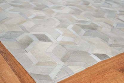 Geometric area rug in grey, taupe and beige patchwork hexagons on a warm wood floor