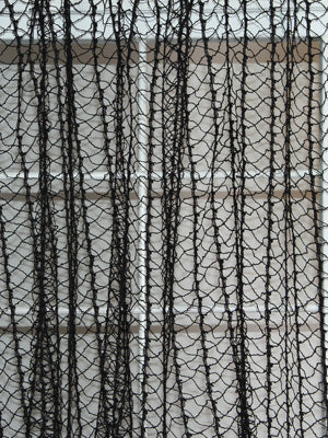 Black macrame string curtain with looped strands forming a sheer decorative panel for windows or doors.