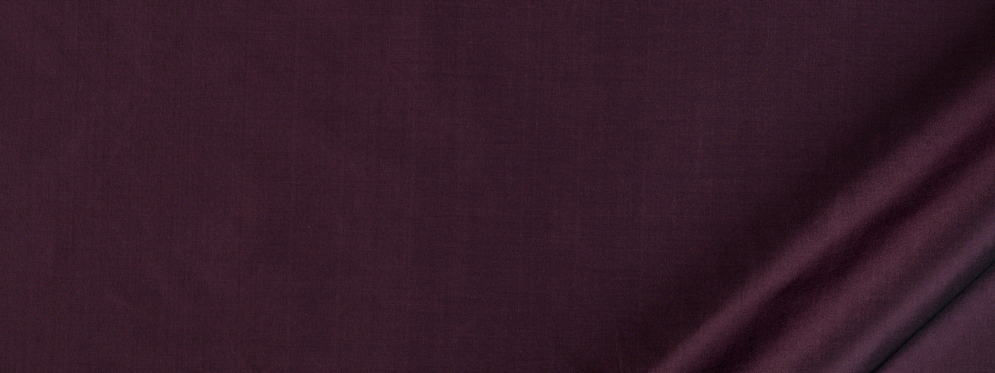 Deep aubergine fabric close-up with soft folds and subtle sheen.