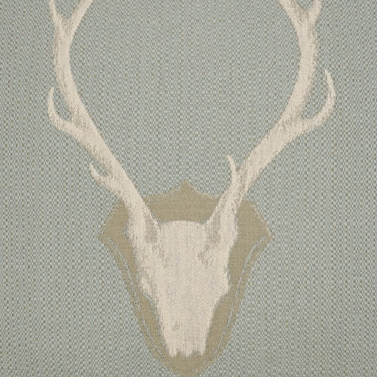 Pillow with a white deer skull and large antlers on a pale blue woven backdrop, 24 x 24 inches.