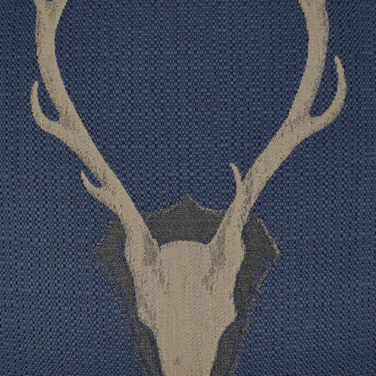 Navy blue pillow with beige deer skull & antlers motif on a woven textile, 24" x 24".