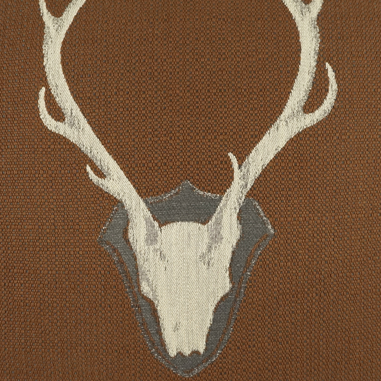 Brown woven pillow featuring a beige deer skull with white antlers on a textured background.