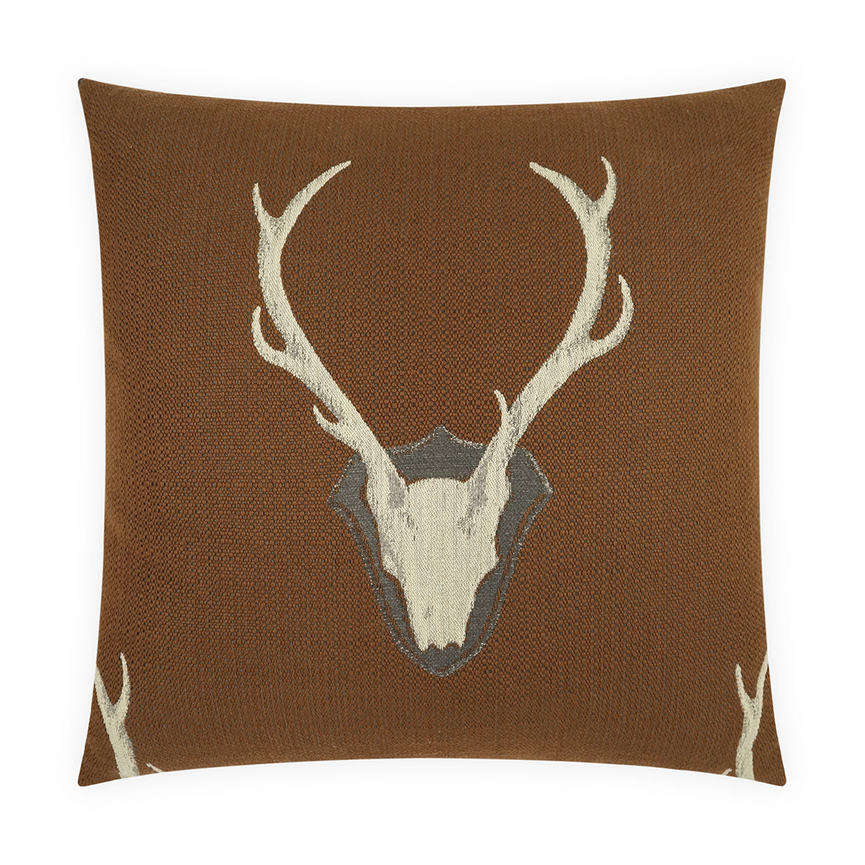 Brown textured square pillow with white deer skull and antlers over a shield motif.