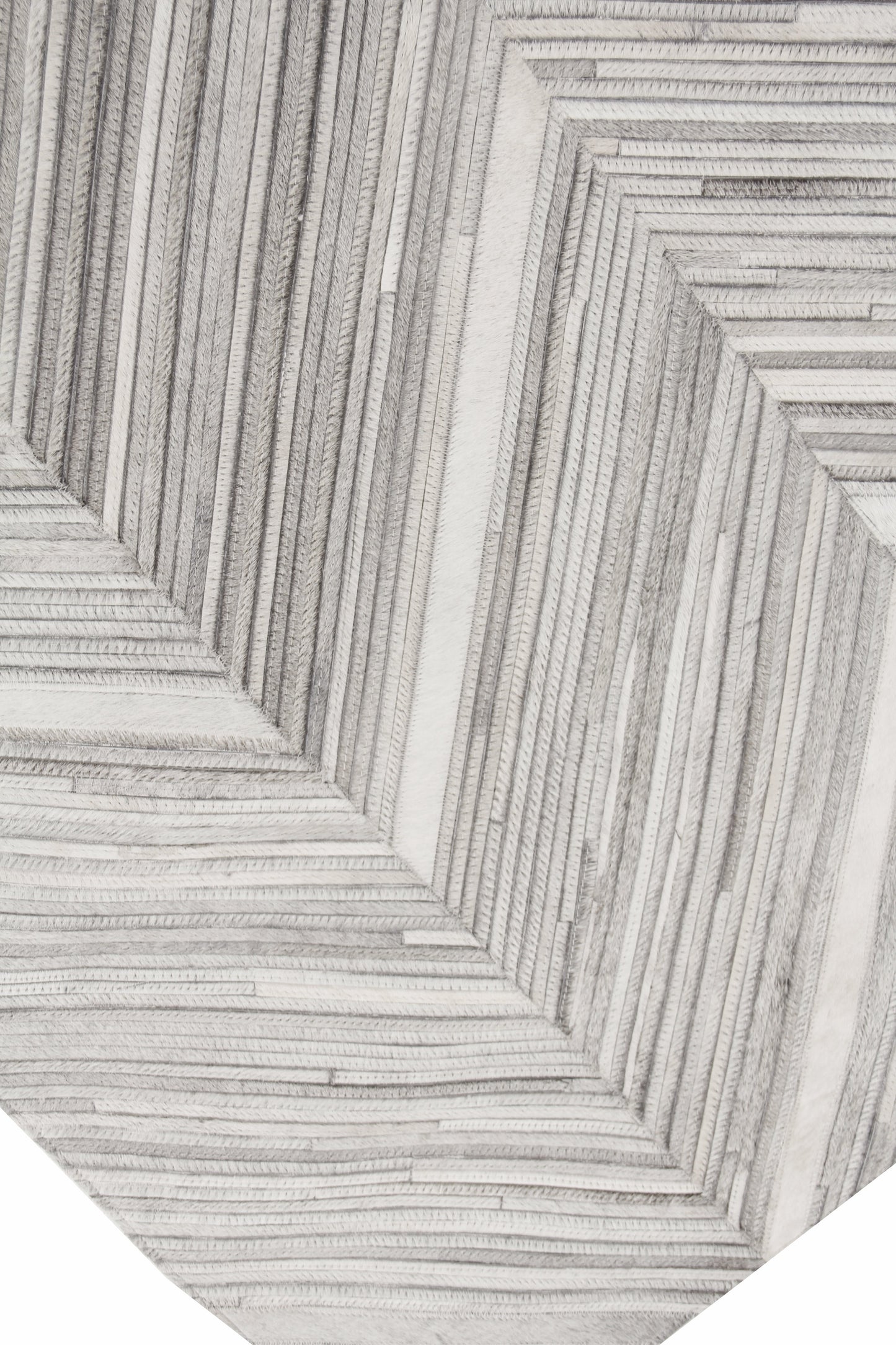 Close-up of a textured cream and gray rug with nested rectangular raised ridges forming a geometric pattern.