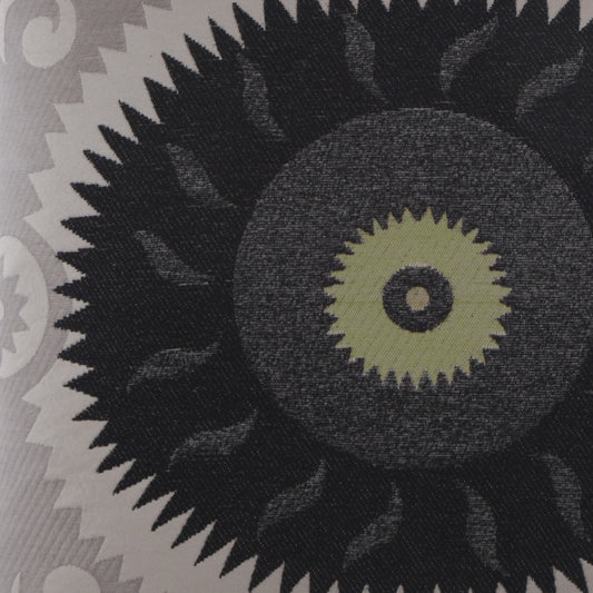 Close-up of fabric featuring a large black sunburst motif with olive-green center on a gray patterned background.
