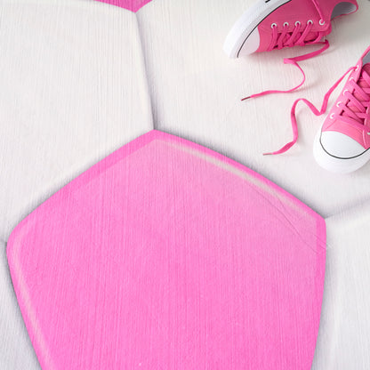 Bright pink round kid's rug on a white surface with pink sneakers and untied laces.