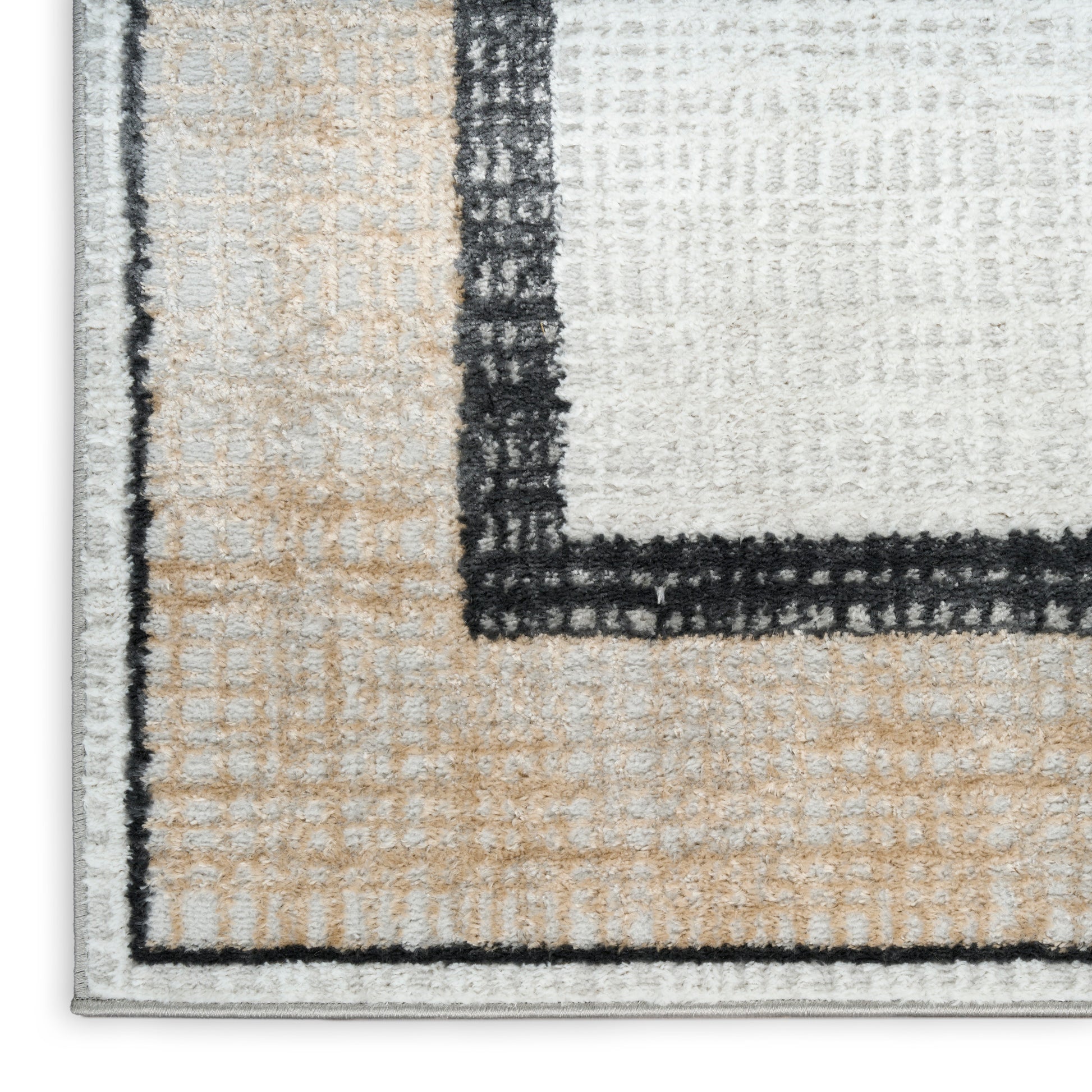 Close-up of a modern geometric area rug with cream, beige and gray blocks, bold black border and shaggy texture.