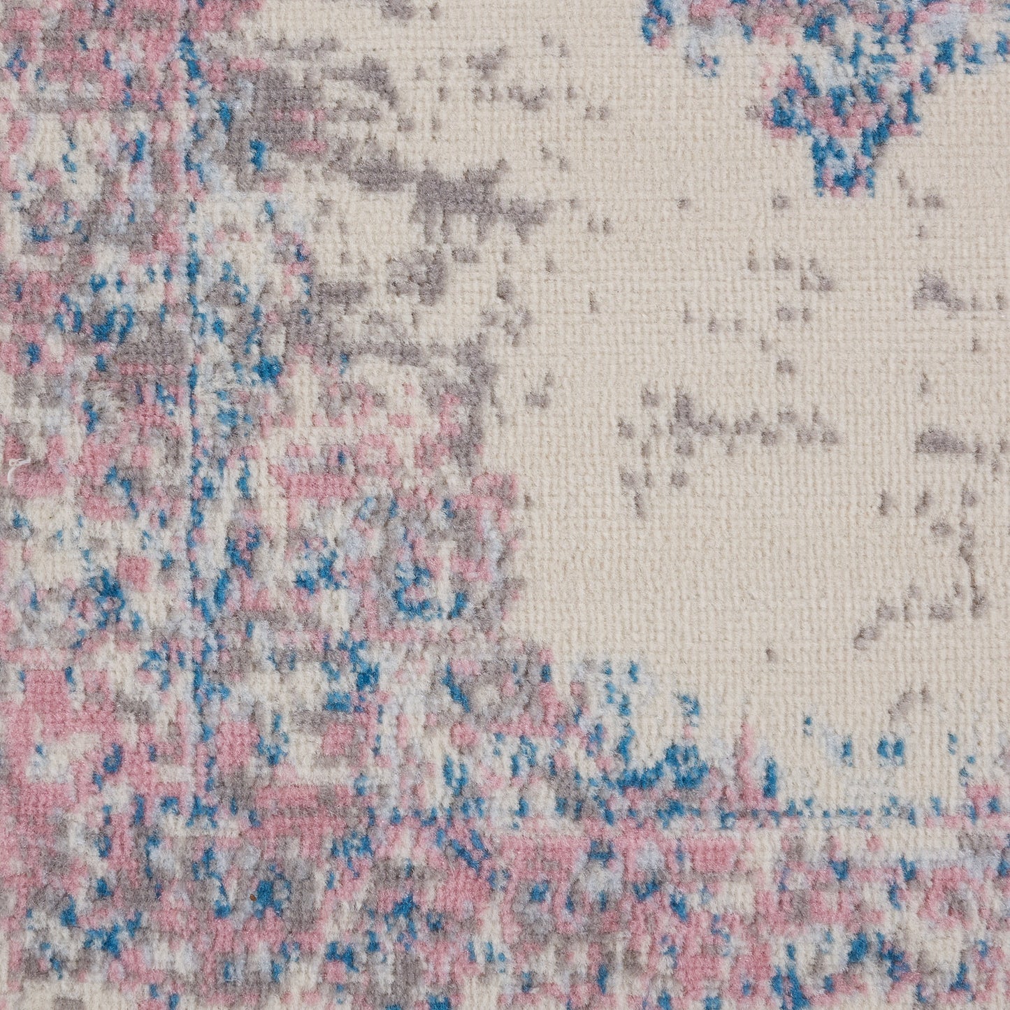 Close-up of a textured vintage runner rug with pink, blue and beige tones in an abstract distressed pattern.