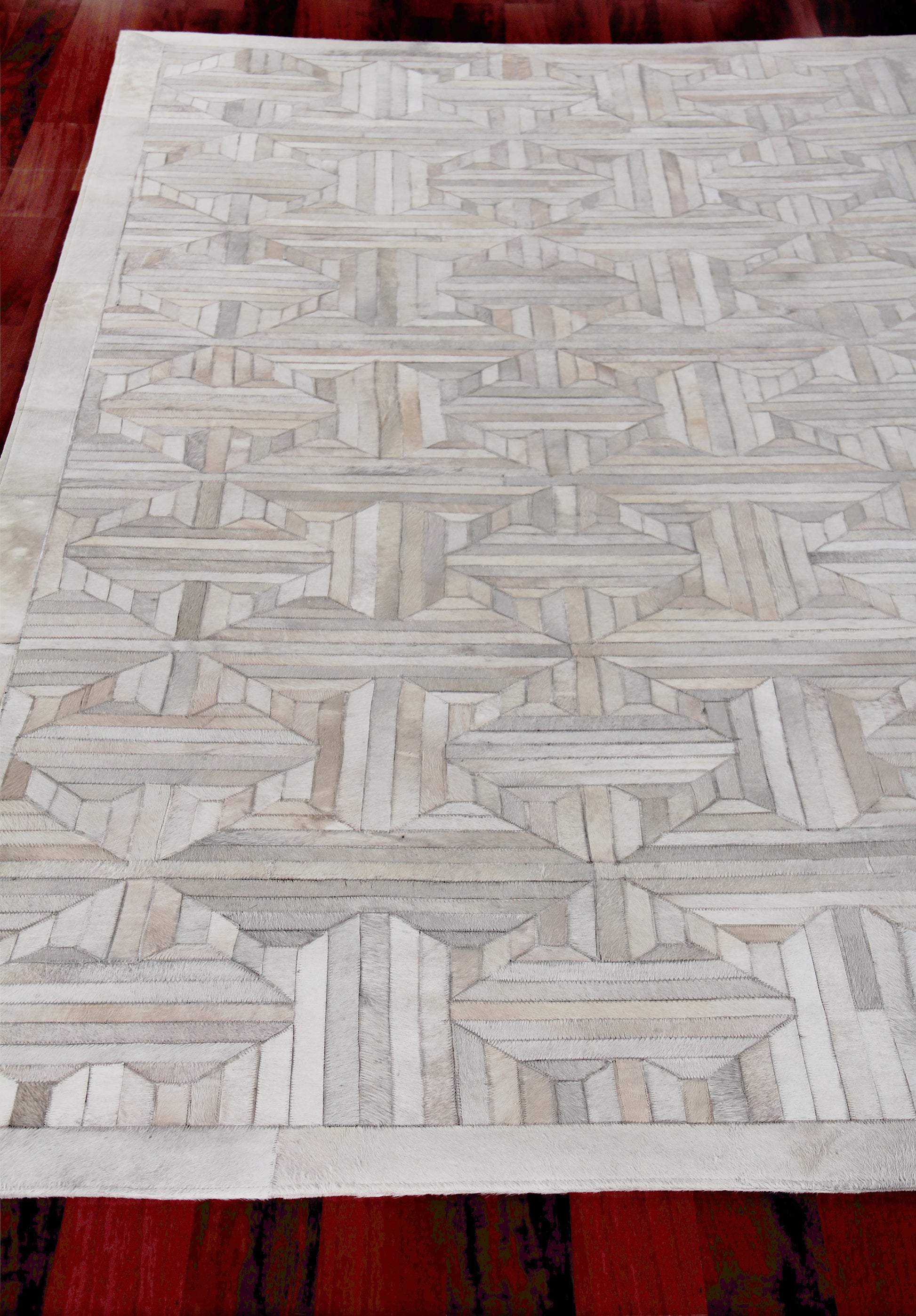 Natural hide indoor hand-stitched area rug in ivory and light gray with a geometric lattice pattern.