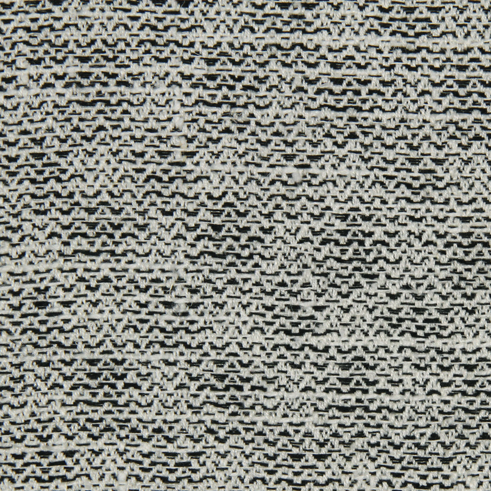 Close-up of black and cream woven knit fabric with a speckled zigzag chevron pattern and textured weave.