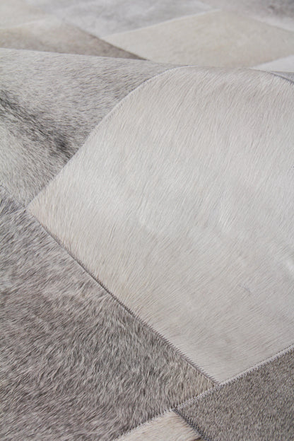 Close-up of a patchwork natural hide rug with grey and white square panels, hand-stitched.