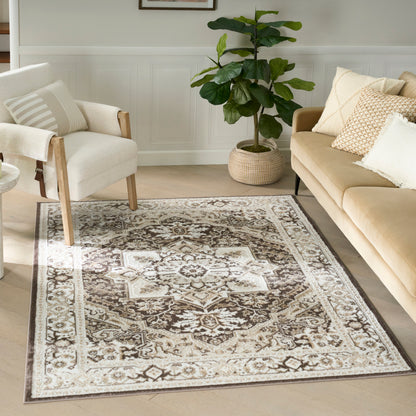 Neutral living room with beige ornate rug, cream armchair, tan sofa, and a tall leafy plant in a woven basket.