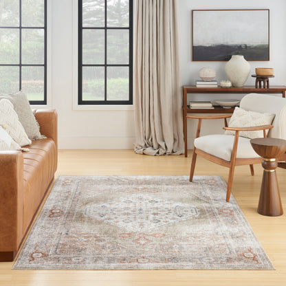 Muted vintage-area rug in cream, blue, and rust; tan leather sofa, mid-century chair, and light wood furnishings.