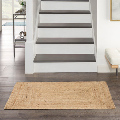 Entryway with white staircase featuring dark wooden treads and a natural jute rug on dark hardwood floor.