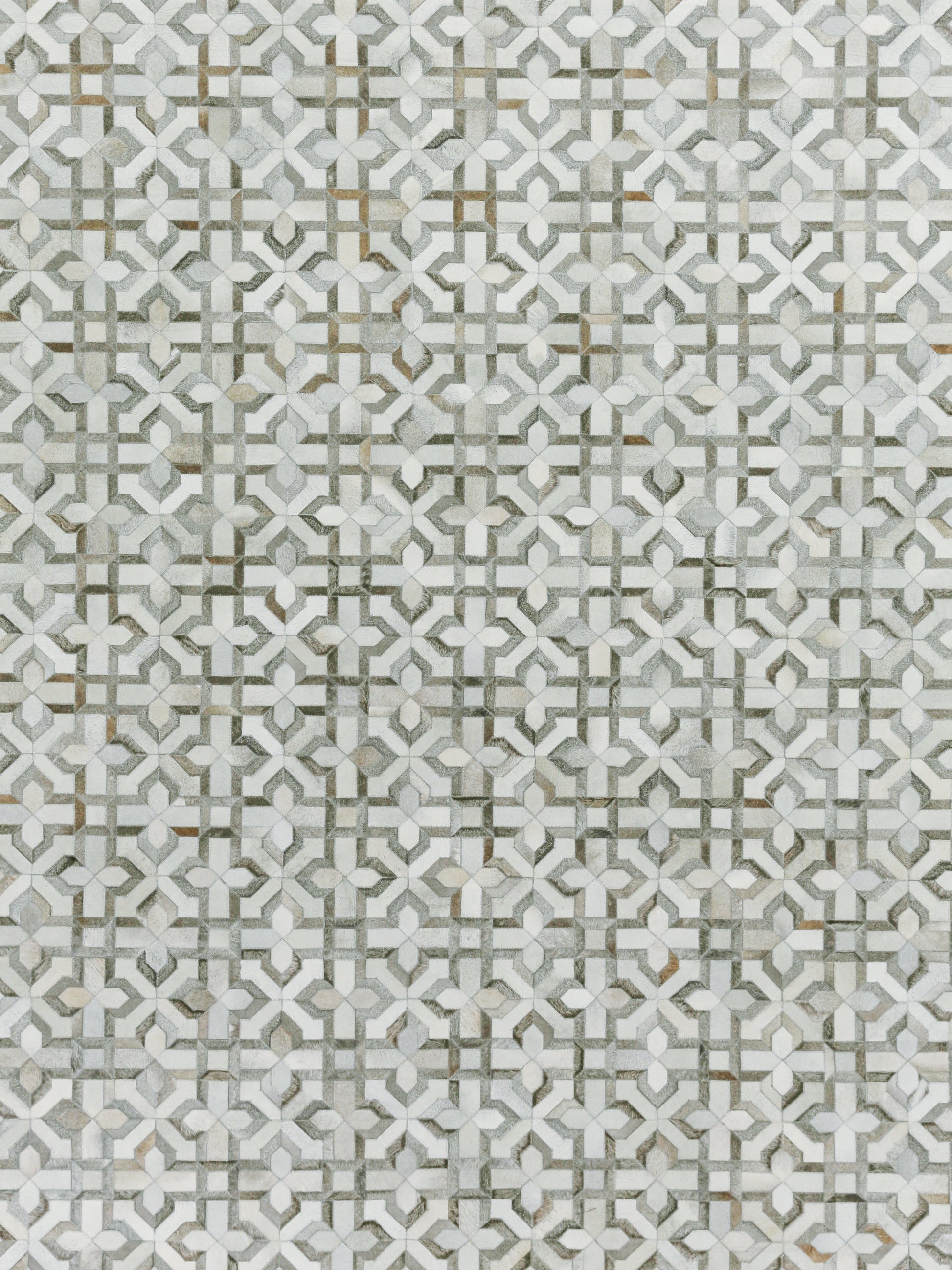 Grey and white geometric pattern on a natural hide rug with interlocking motifs and subtle gold accents; hand-stitched.