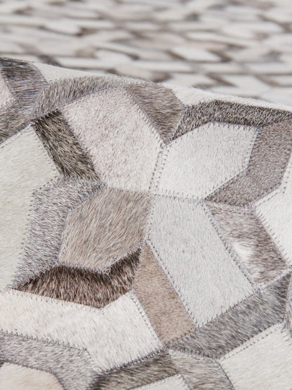 Geometric patchwork natural hide rug in neutral grays, creams and beiges with hexagonal panels.