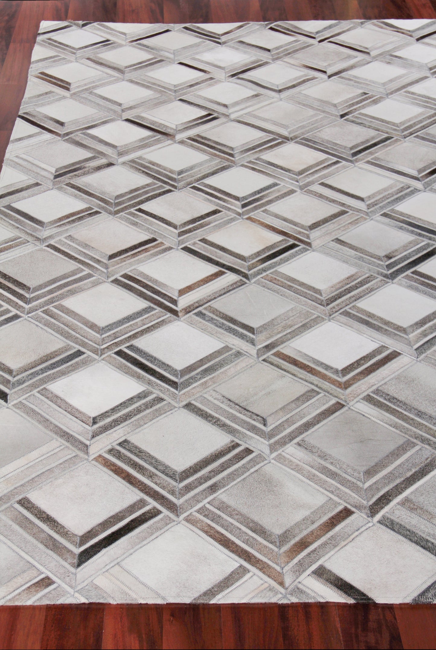 Geometric grey and beige rug with interlocking 3D diamond cube pattern on wooden floor.