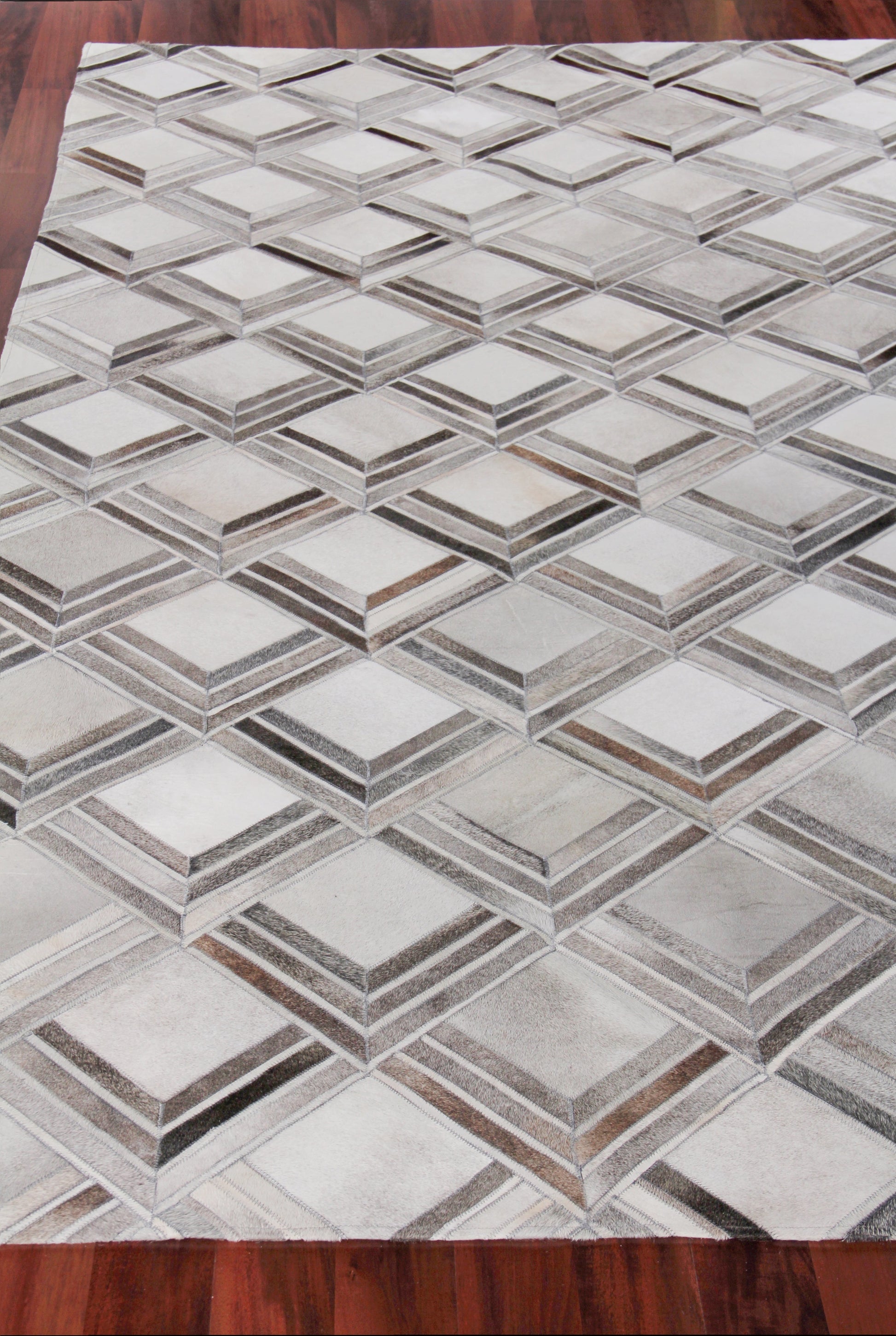 Geometric grey and beige rug with interlocking 3D diamond cube pattern on wooden floor.