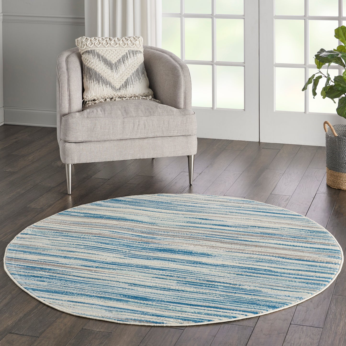 Round blue & cream striped woven rug in a contemporary living room beside a light gray armchair.