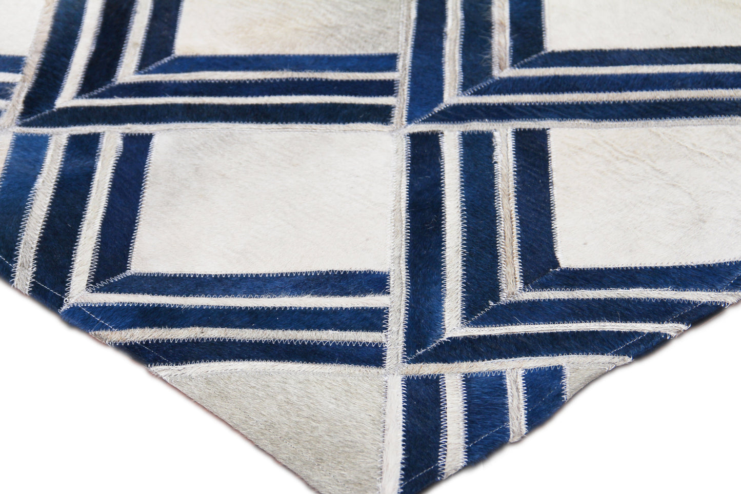 Natural hide indoor hand-stitched rug featuring a geometric blue and ivory interlocking square pattern with navy borders and fringed edges.
