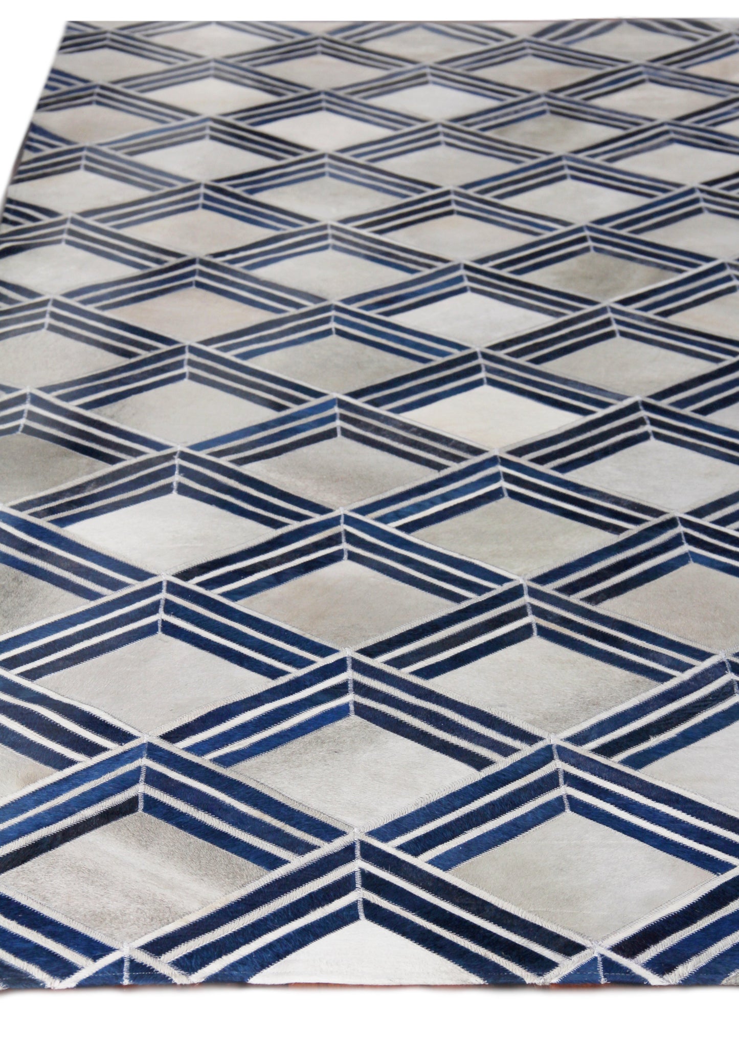 Natural hide indoor hand-stitched rug with a geometric pattern featuring navy blue chevron diamonds on a light gray background.