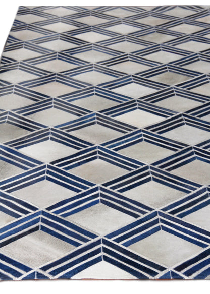 Natural hide indoor hand-stitched rug with a geometric pattern featuring navy blue chevron diamonds on a light gray background.