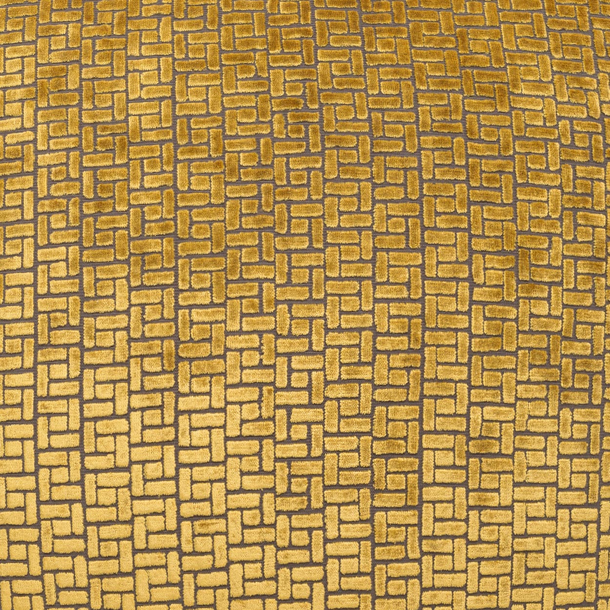 Gold-toned fabric with a repeating interlocking brick-like tile pattern in warm bronze hues.