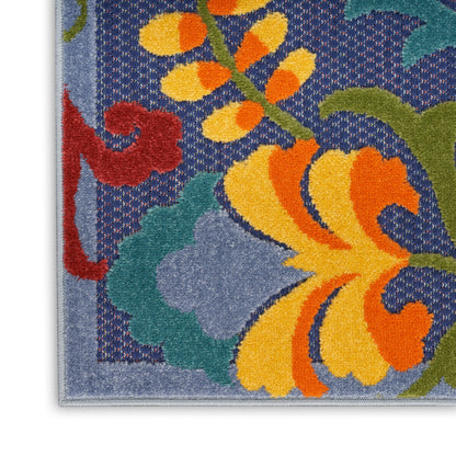 Close-up of blue floral area rug with bright yellow and orange petals, green leaves, and red vine accents.