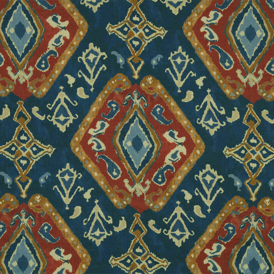 Blue field ikat-style rug with repeating red diamond medallions, turquoise centers and gold-cream geometric detailing.