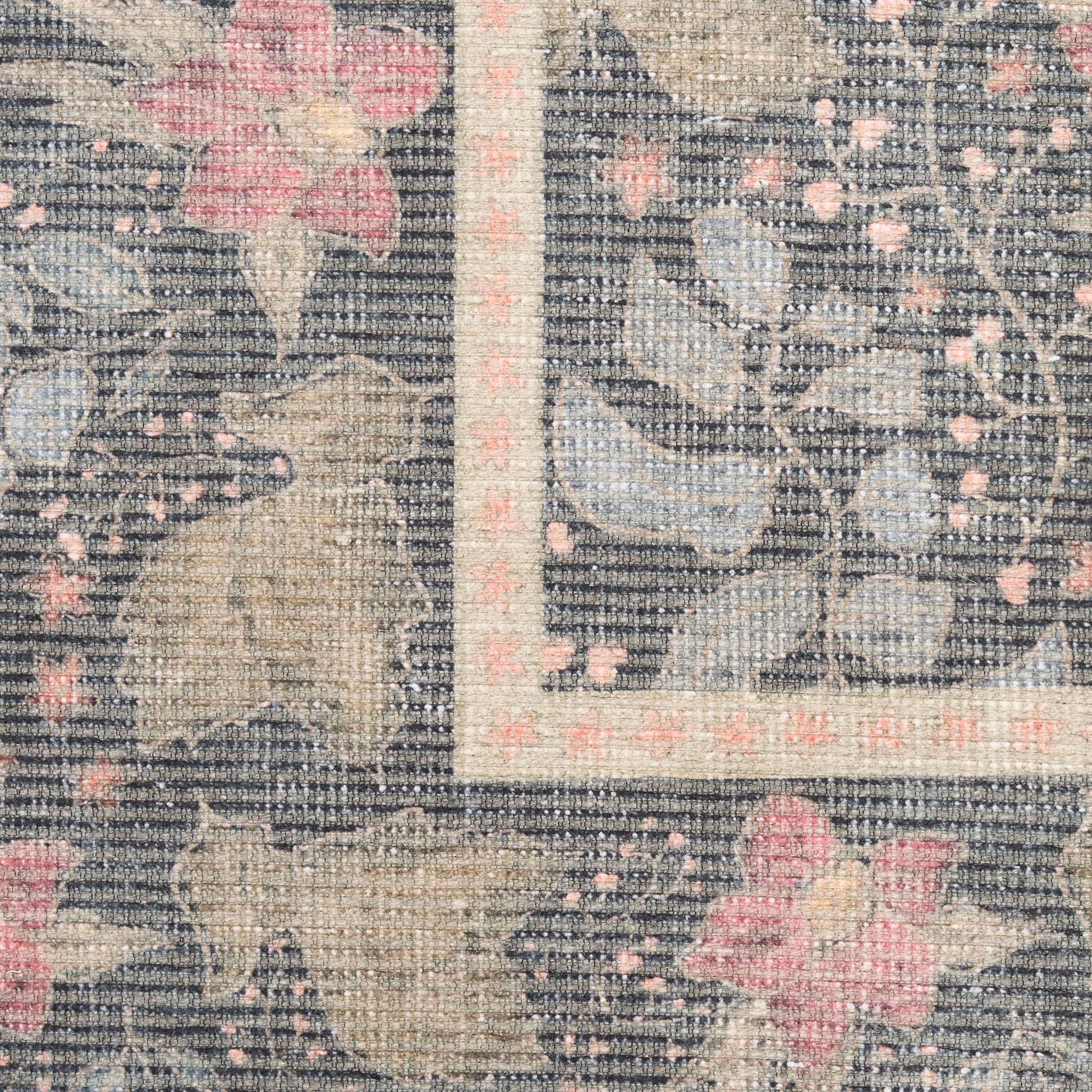 Close-up of a traditional floral rug with gray-blue ground, beige leaves and pink blossoms, bordered by a pale pink frame.