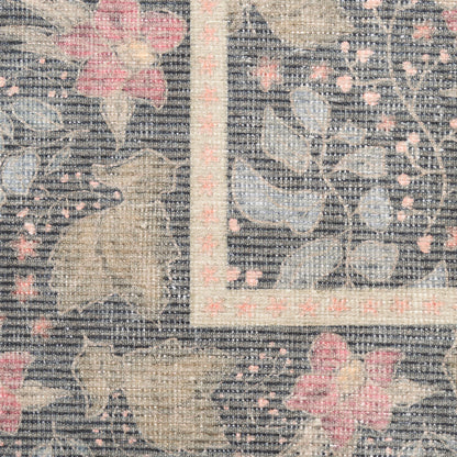 Close-up of a traditional floral rug with gray-blue ground, beige leaves and pink blossoms, bordered by a pale pink frame.