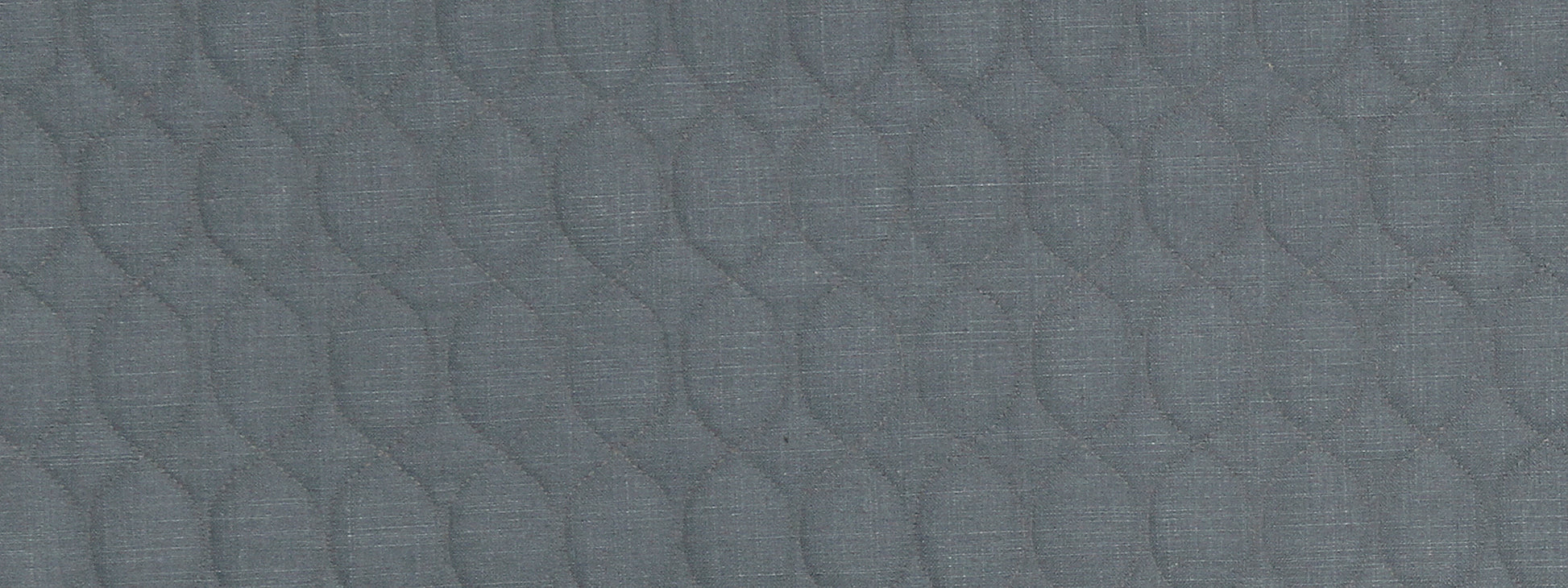 Close-up of blue-gray quilted fabric with repeating teardrop-shaped stitched pattern.