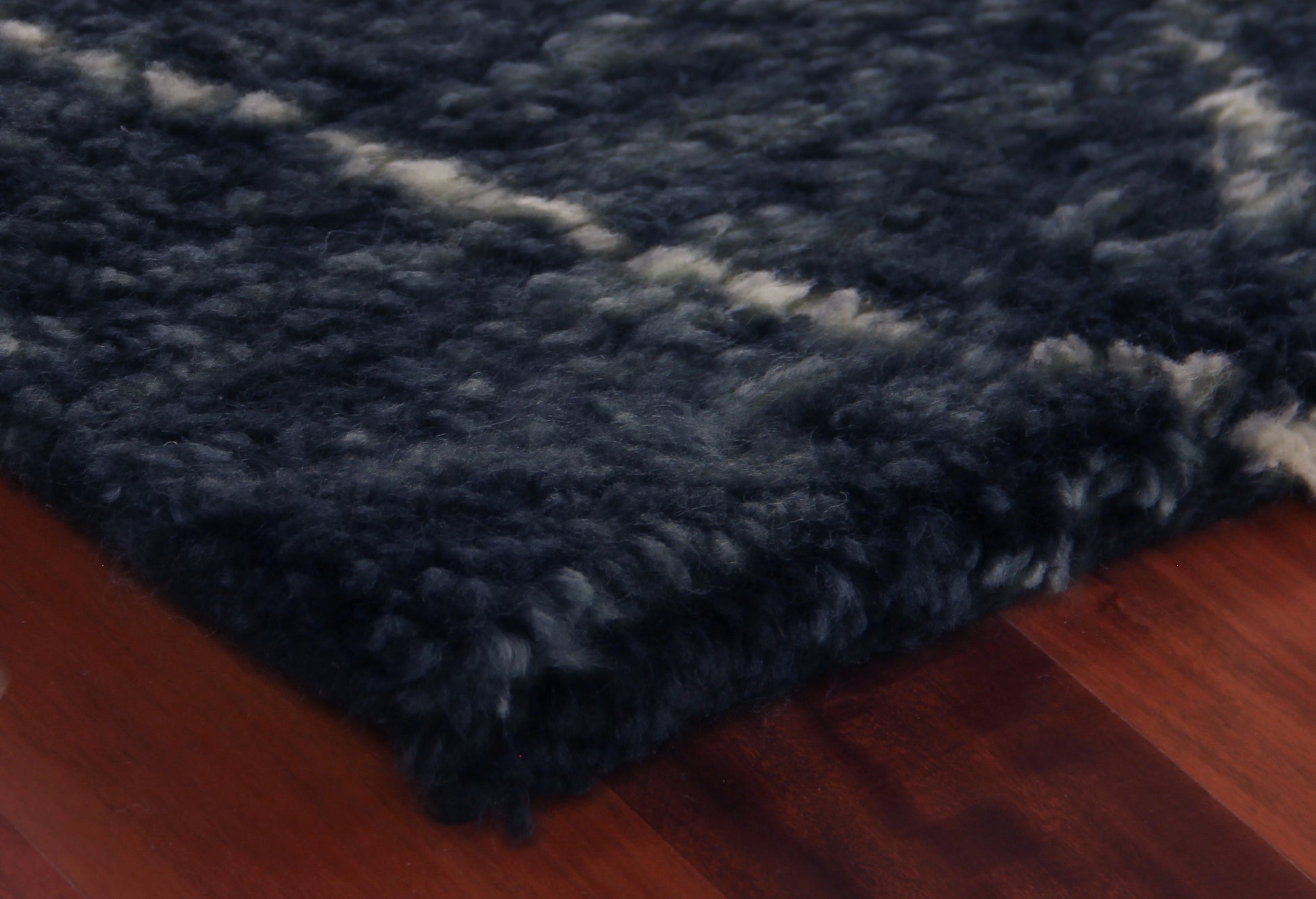 Dark navy Moroccan indoor hand-knotted rug on warm wood floor.