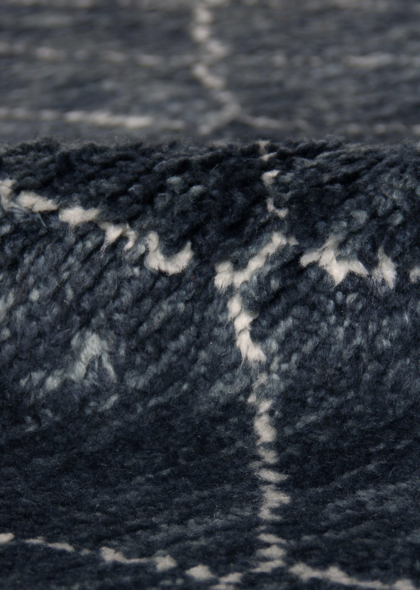 Close-up of navy blue Moroccan indoor hand-knotted rug with white geometric pattern.