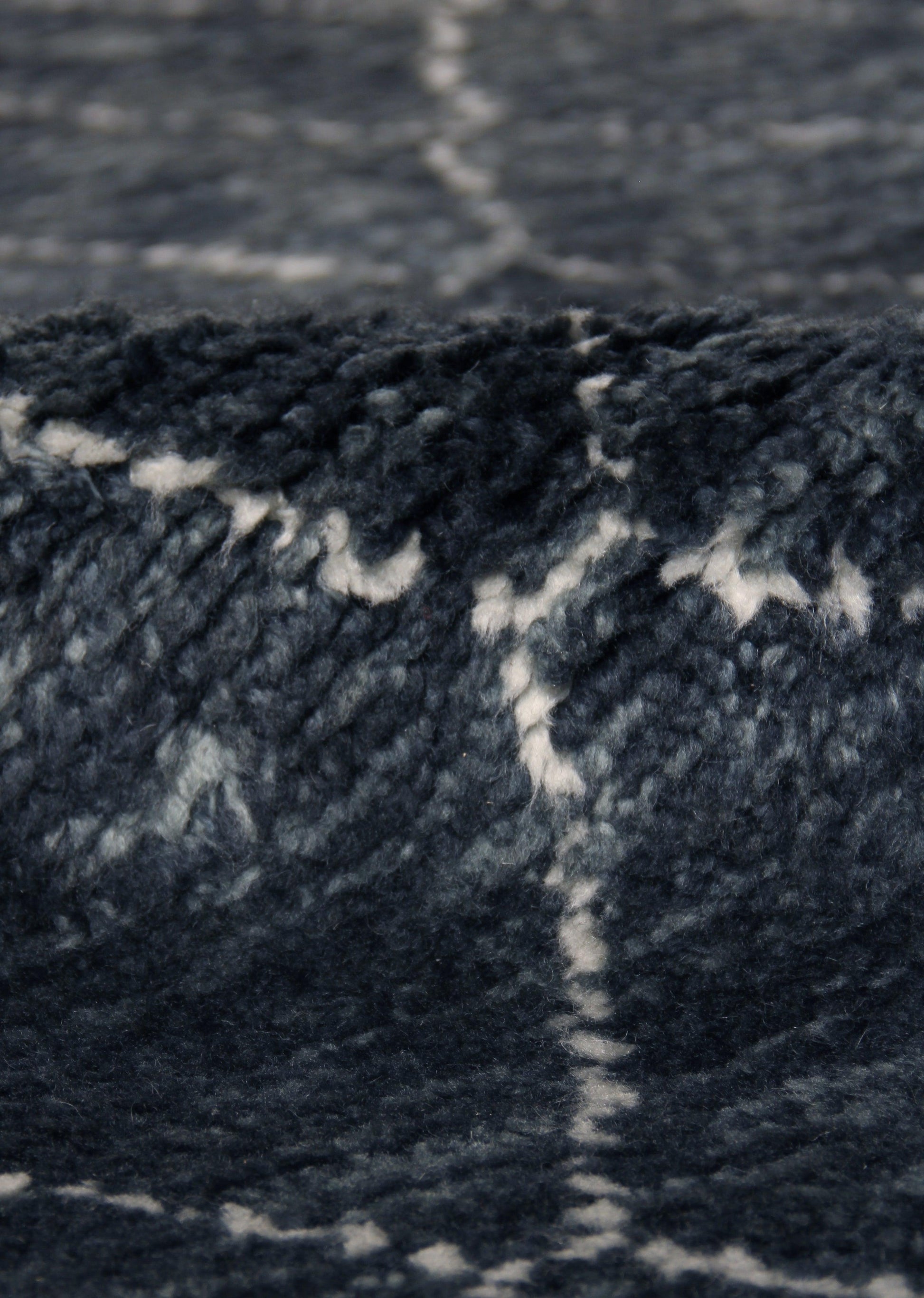Close-up of navy blue Moroccan indoor hand-knotted rug with white geometric pattern.