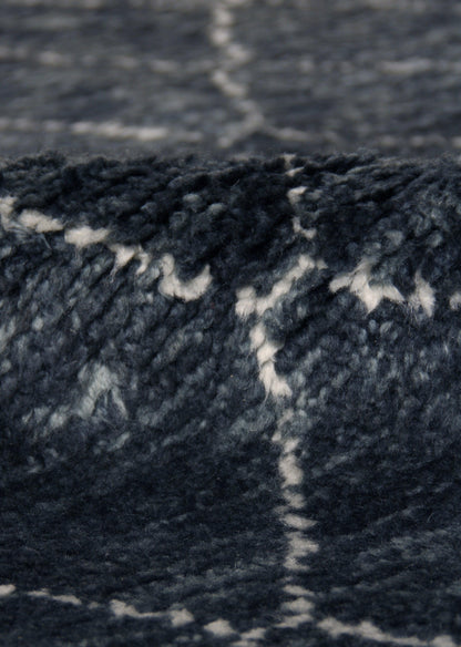 Close-up of navy blue Moroccan indoor hand-knotted rug with white geometric pattern.